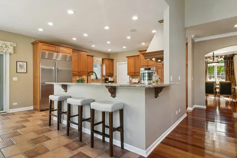 a kitchen with stainless steel appliances kitchen island granite countertop a table and chairs in it