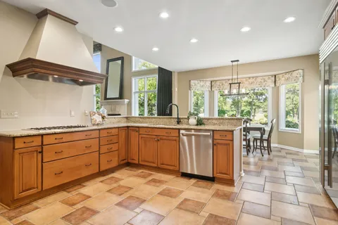 a large kitchen with kitchen island granite countertop a large dining table and a large window