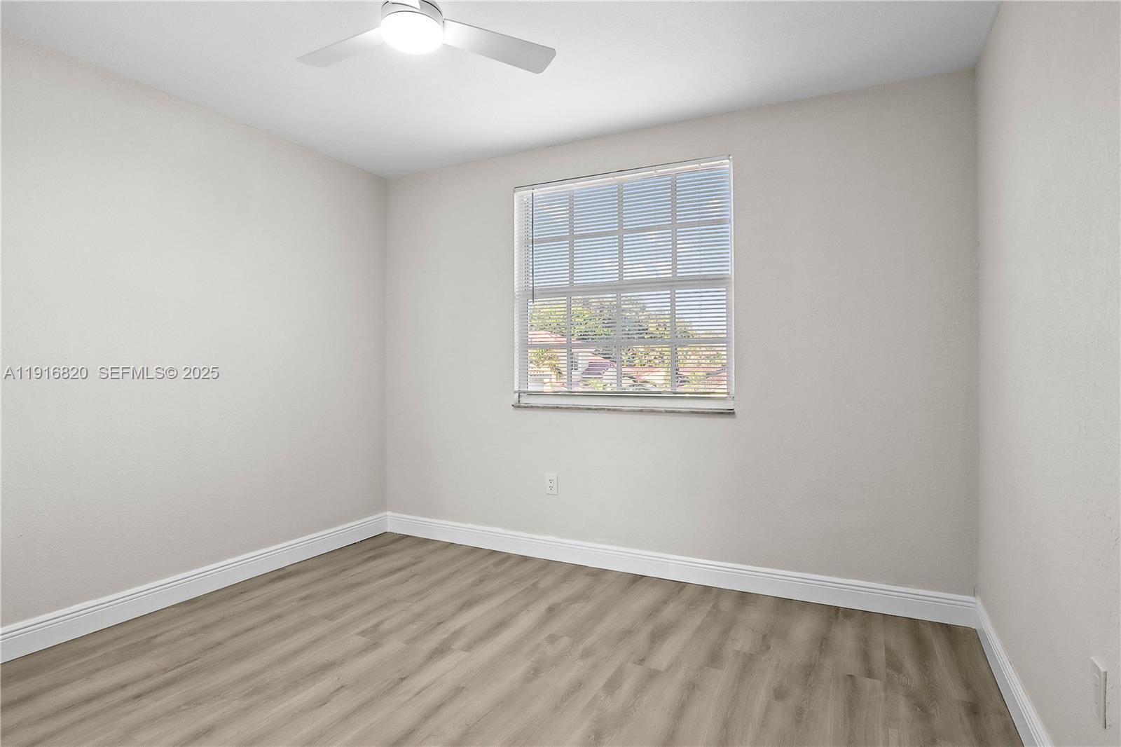 1223 Northwest 125th Terrace Sunrise, FL 33323 - Photo 60 of 89 an empty room with wooden floor and windows