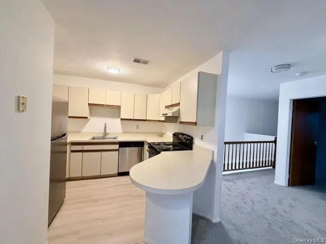 a kitchen with a sink a stove a refrigerator and white cabinets