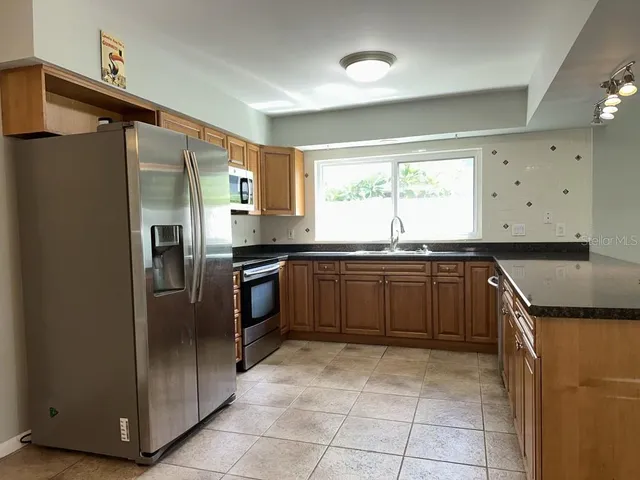 a kitchen with granite countertop a refrigerator and a sink