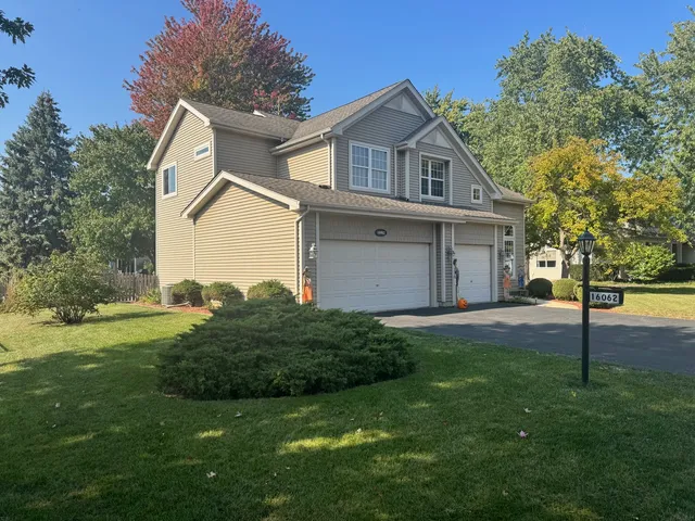 a view of a yard in front of a house with plants and large tree