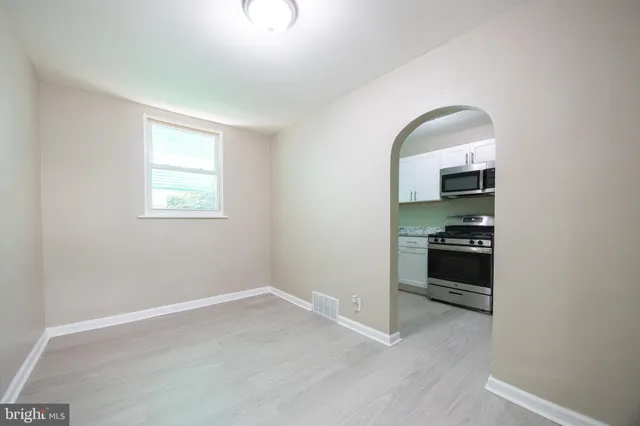 an empty room with wooden floor cabinet and a window