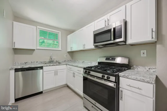 a kitchen with granite countertop white cabinets stainless steel appliances and a sink