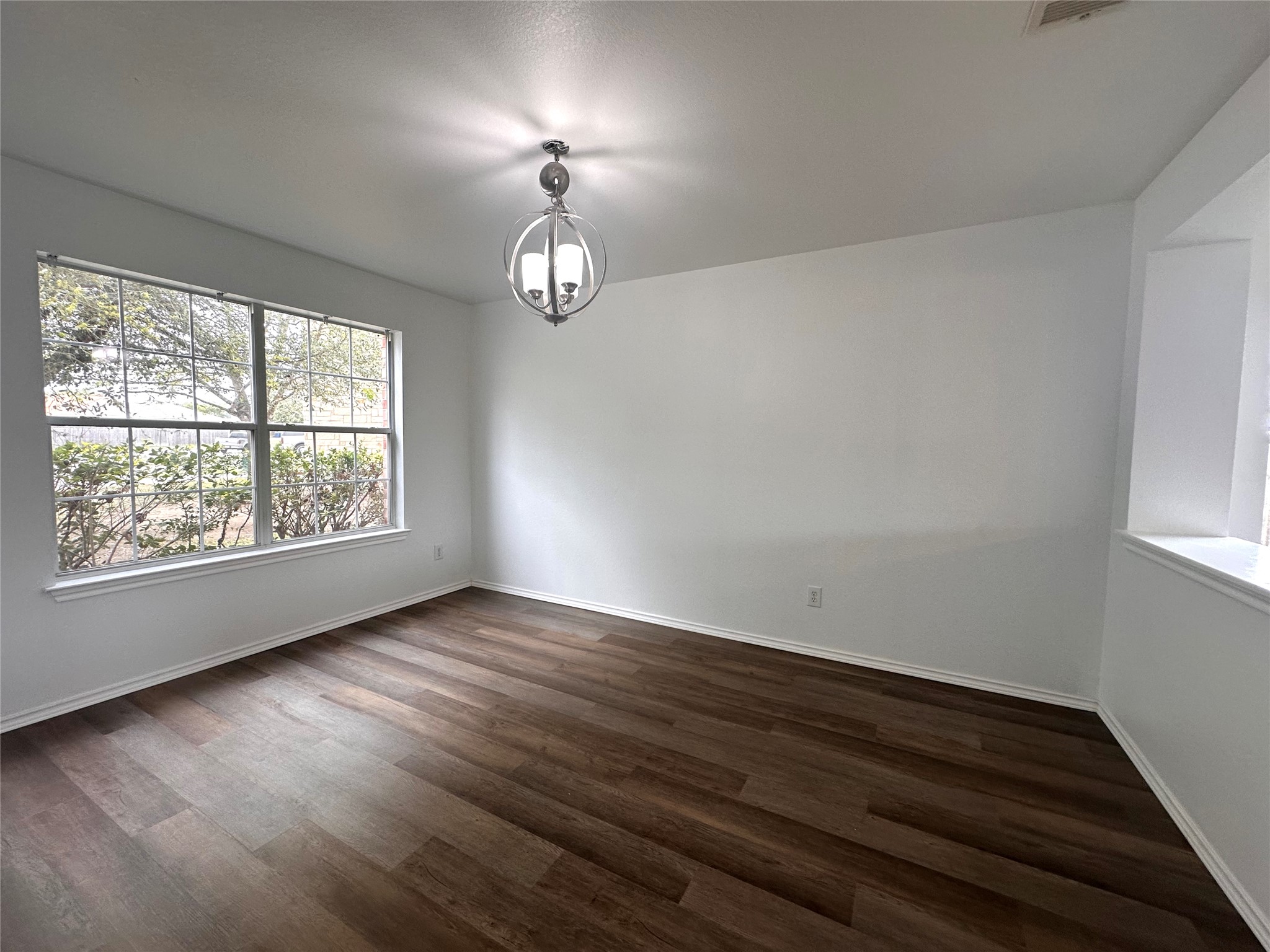 722 Lavaca Loop Elgin, TX 78621 - Photo 3 of 24 Empty room with dark wood-type flooring and hanging lights