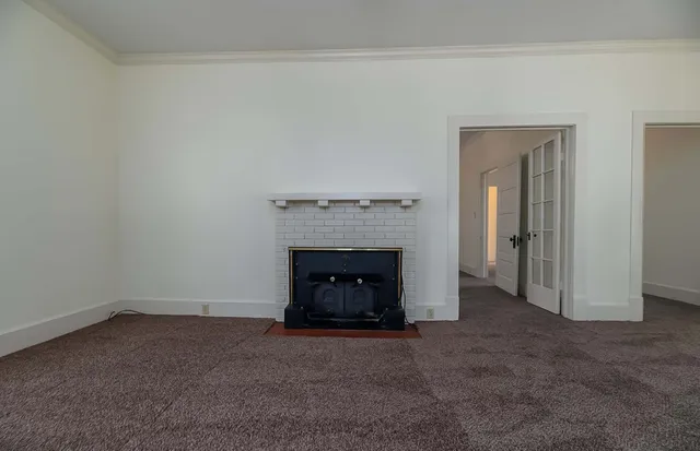 an empty room with windows and fireplace