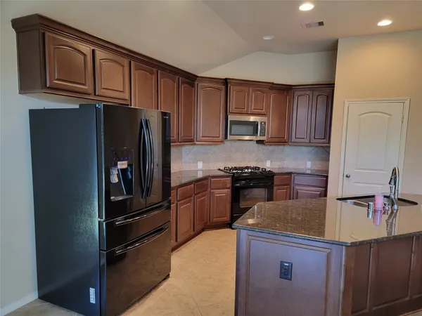 a kitchen with a refrigerator sink and cabinets