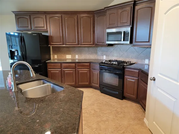 a kitchen with granite countertop a stove sink and refrigerator