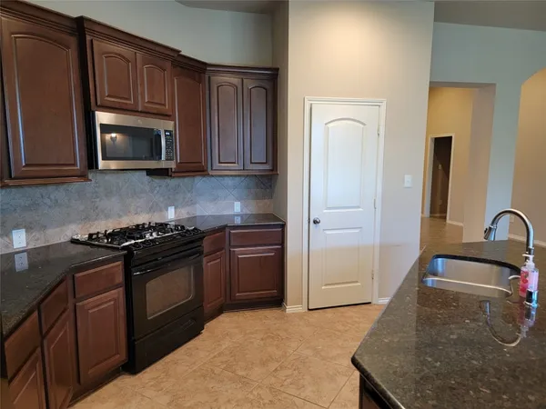 a kitchen with granite countertop wooden cabinets and stainless steel appliances