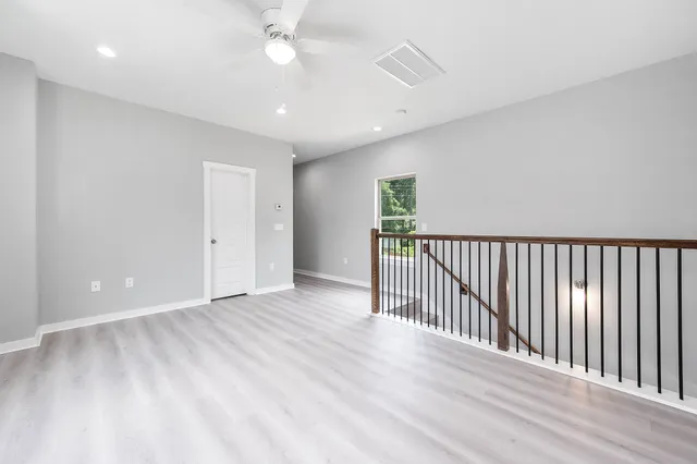 a view of a room with wooden floor fan and windows
