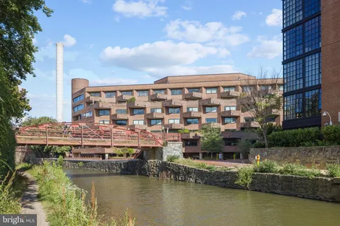 a view of swimming pool with seating space and trees in the background