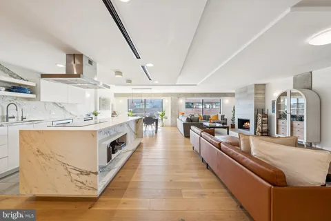 a large white open kitchen with stainless steel appliances kitchen island granite countertop a large counter top and a stove