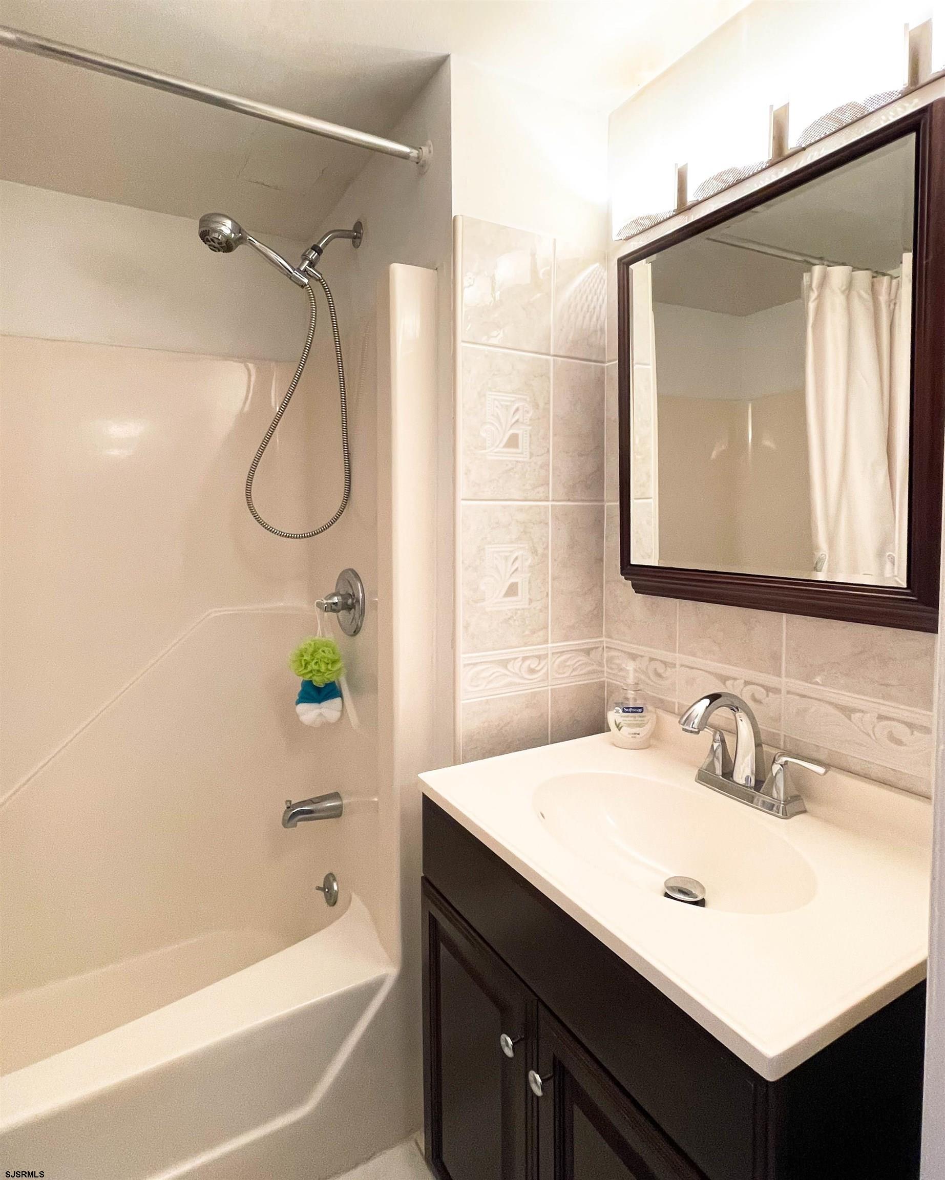 9201 Atlantic Avenue, Unit 2 Margate City, NJ 08402 - Photo 11 of 13 a bathroom with a tub sink and mirror