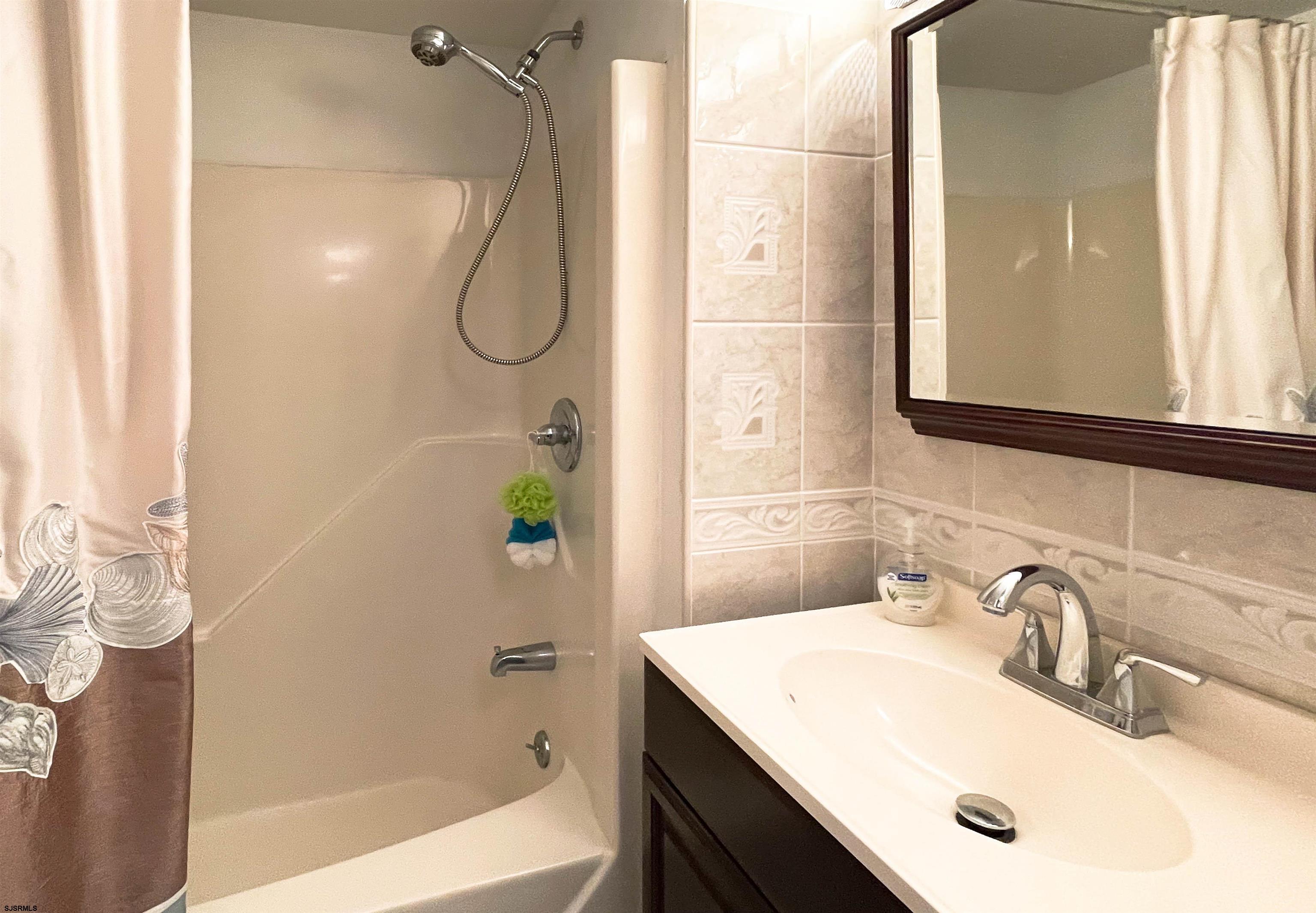 9201 Atlantic Avenue, Unit 2 Margate City, NJ 08402 - Photo 12 of 13 a bathroom with a sink vanity mirror and shower