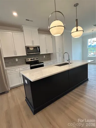 a kitchen with stainless steel appliances granite countertop a sink a stove and a wooden floor