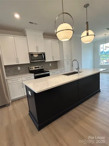 a kitchen with stainless steel appliances granite countertop a sink a stove and a wooden floor