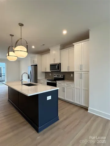 a kitchen with stainless steel appliances granite countertop a sink a stove a refrigerator and island with wooden floor