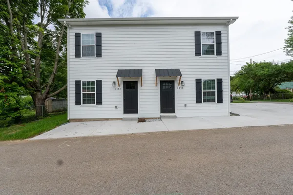 a white house with a yard and parking space