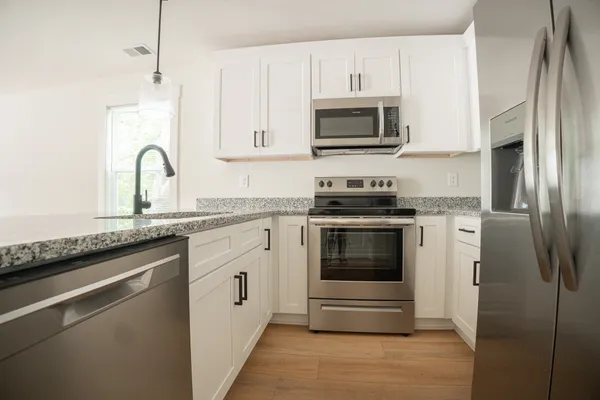 a kitchen with granite countertop white cabinets and stainless steel appliances