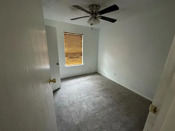 an empty room with a window and a fan