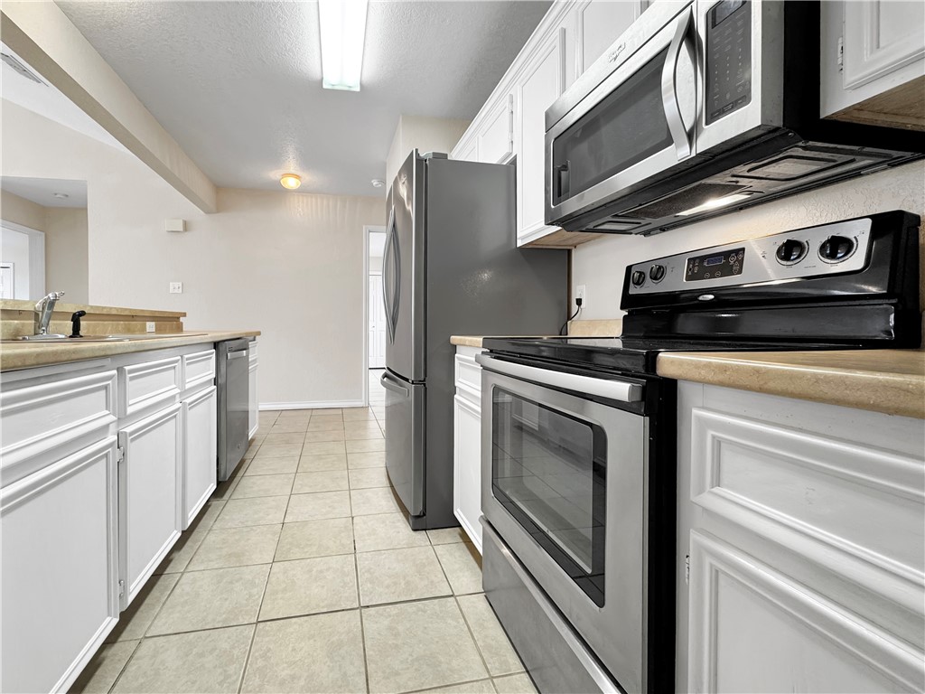 14302 Cruiser Street, Unit B Corpus Christi, TX 78418 - Photo 14 of 25 a kitchen with stainless steel appliances granite countertop a stove and a refrigerator