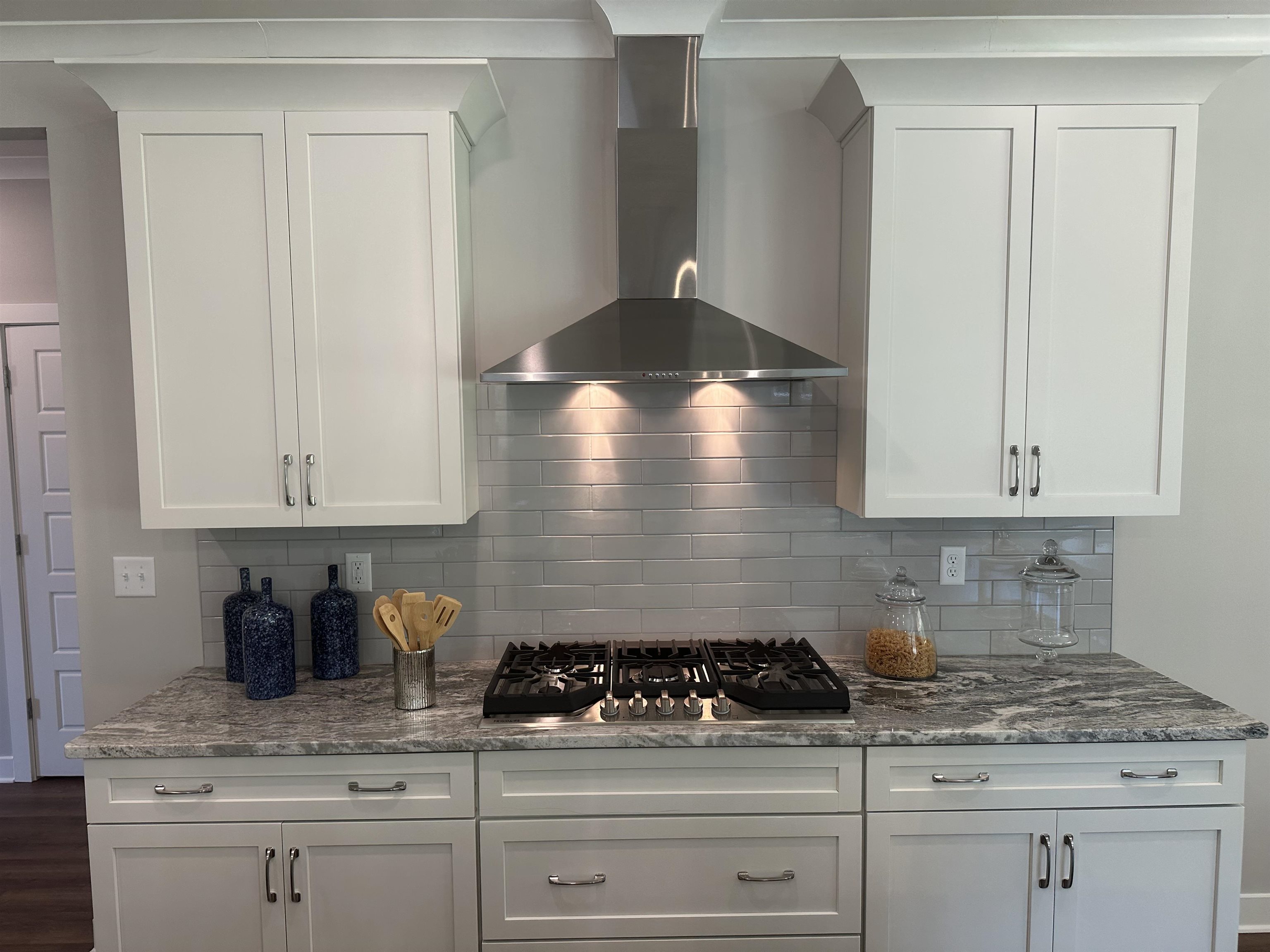 10147 Conner Field Lane Lakeland, TN 38002 - Photo 17 of 28 Kitchen with wall chimney exhaust hood, backsplash, stainless steel gas cooktop, and white cabinetry