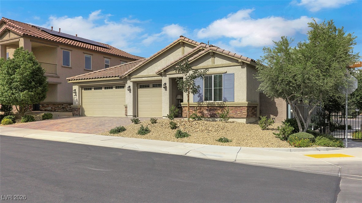 View of front of property featuring stucco siding, driveway, an attached garage, and brick siding