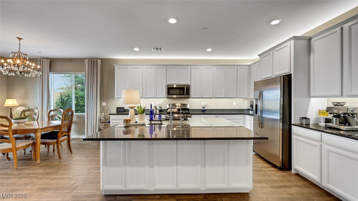 1094 Langston Ranch Avenue Henderson, NV 89002 - Photo 4 of 70 Kitchen featuring stainless steel appliances, dark stone counters, recessed lighting, light wood finished floors, and white cabinetry