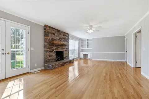 an empty room with windows fireplace and wooden floor
