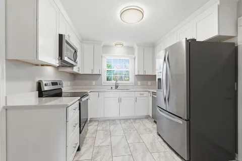 a kitchen with a refrigerator sink and cabinets