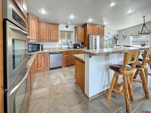 a kitchen with kitchen island granite countertop wooden cabinets and stainless steel appliances