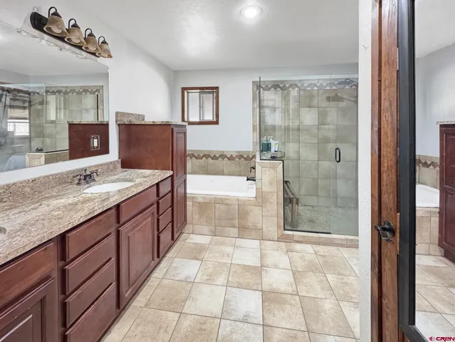 a spacious bathroom with a granite countertop sink a mirror and a shower