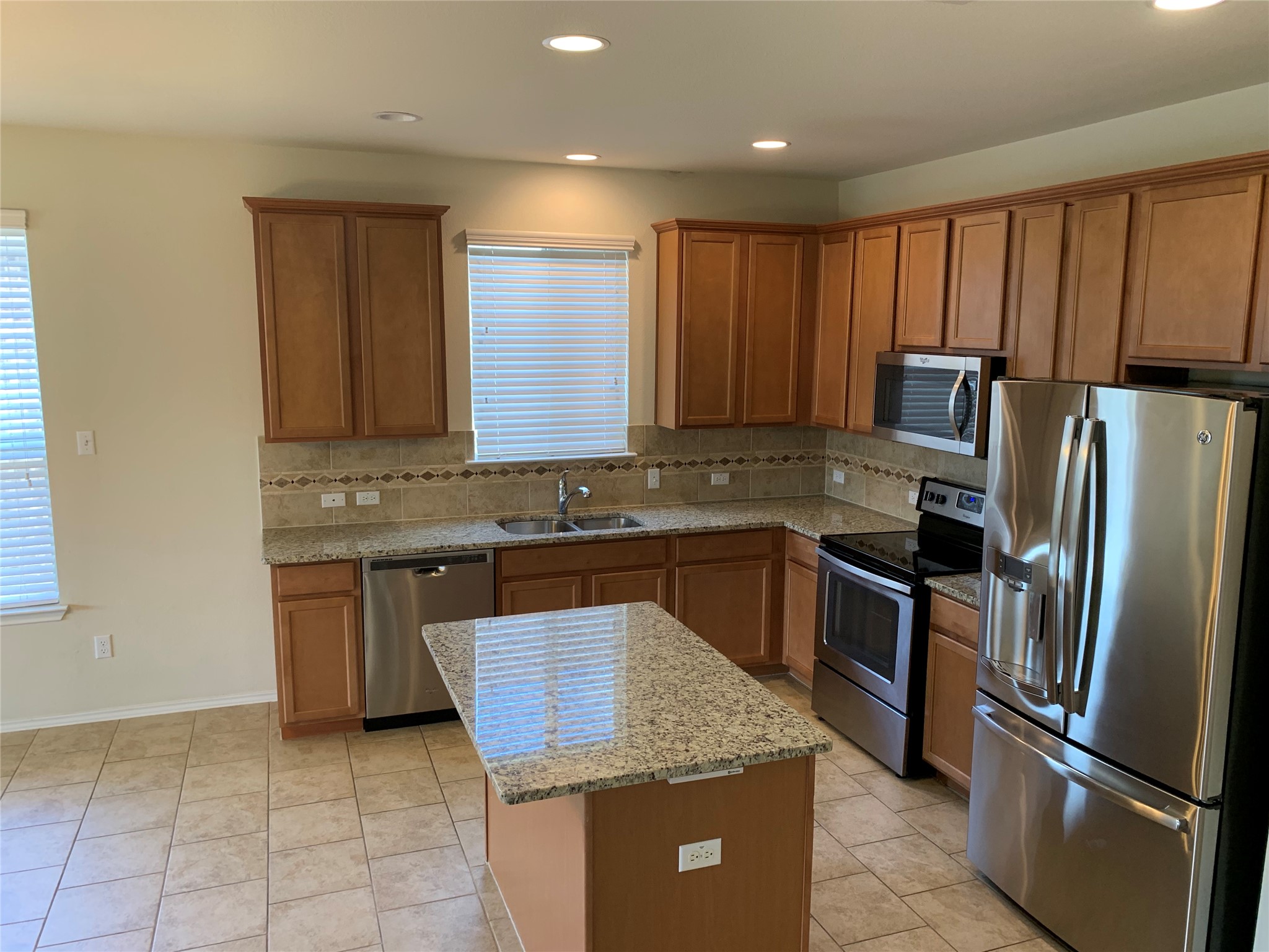 113 Sierra Mar Loop Leander, TX 78641 - Photo 9 of 22 a kitchen with granite countertop stainless steel appliances a refrigerator a stove a sink cabinets and a counter top space