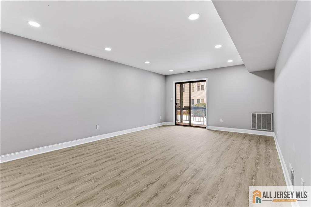 809 Woodbridge Commons Way, Unit 809 Iselin, NJ 08830 - Photo 5 of 16 an empty room with wooden floor and sliding door