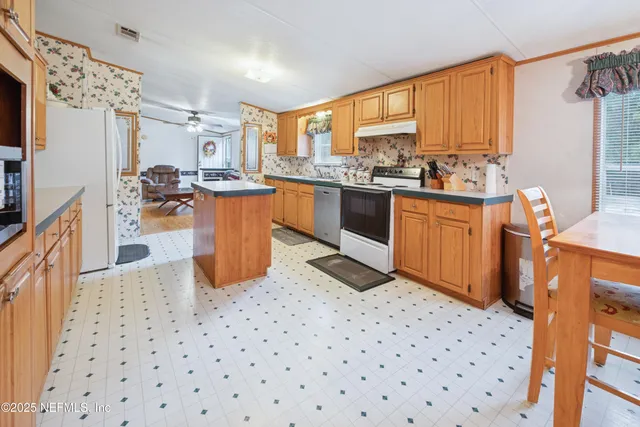a kitchen with stainless steel appliances a sink a stove a refrigerator cabinets and a window