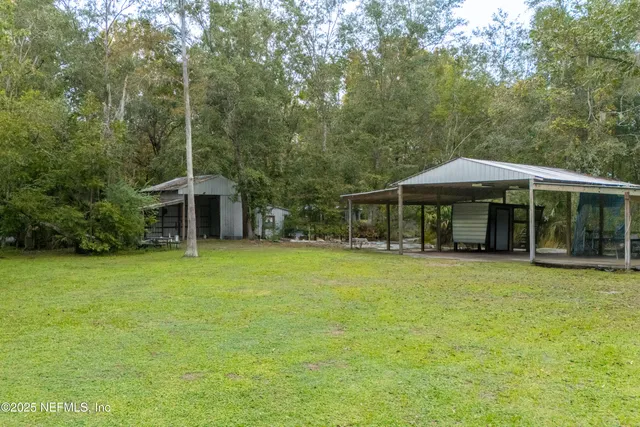 a backyard of a house with table and chairs under an umbrella
