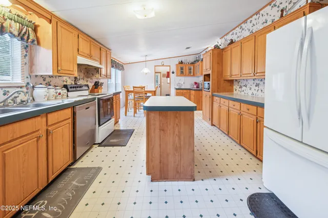 a kitchen with stainless steel appliances granite countertop a refrigerator a sink dishwasher and wooden cabinets with wooden floor