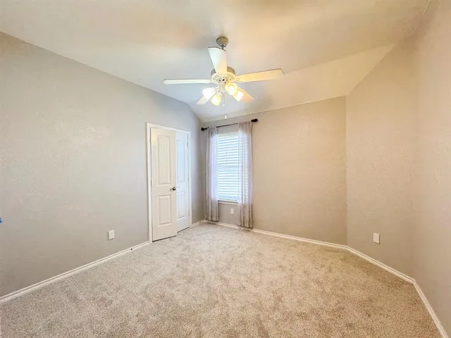 an empty room with a chandelier fan and windows