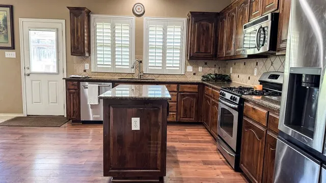 a kitchen with stainless steel appliances granite countertop a stove a sink and a microwave