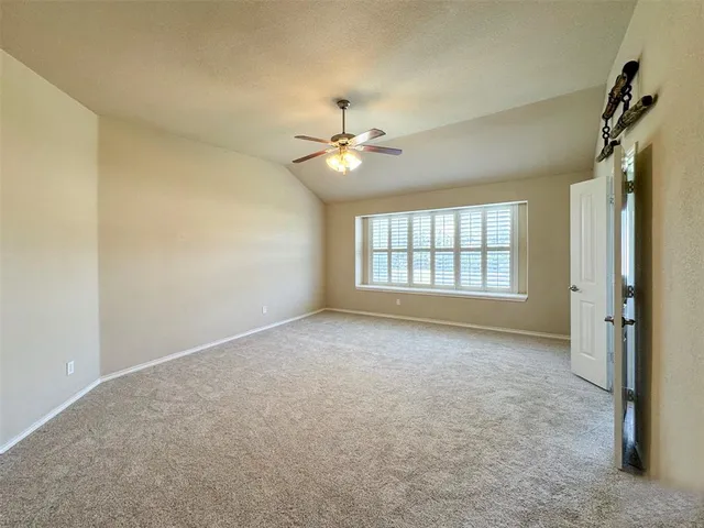 an empty room with windows and ceiling fan