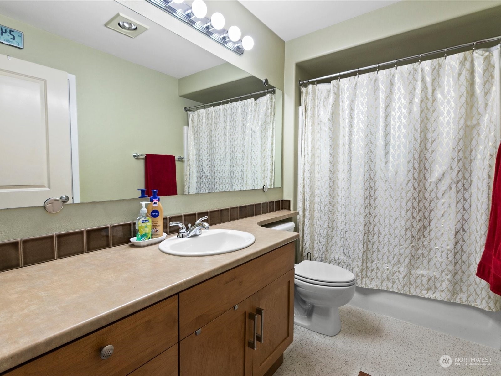 3015 Southwest Avalon Way, Unit 407 Seattle, WA 98126 - Photo 8 of 27 a bathroom with a granite countertop sink a toilet a mirror and shower curtain