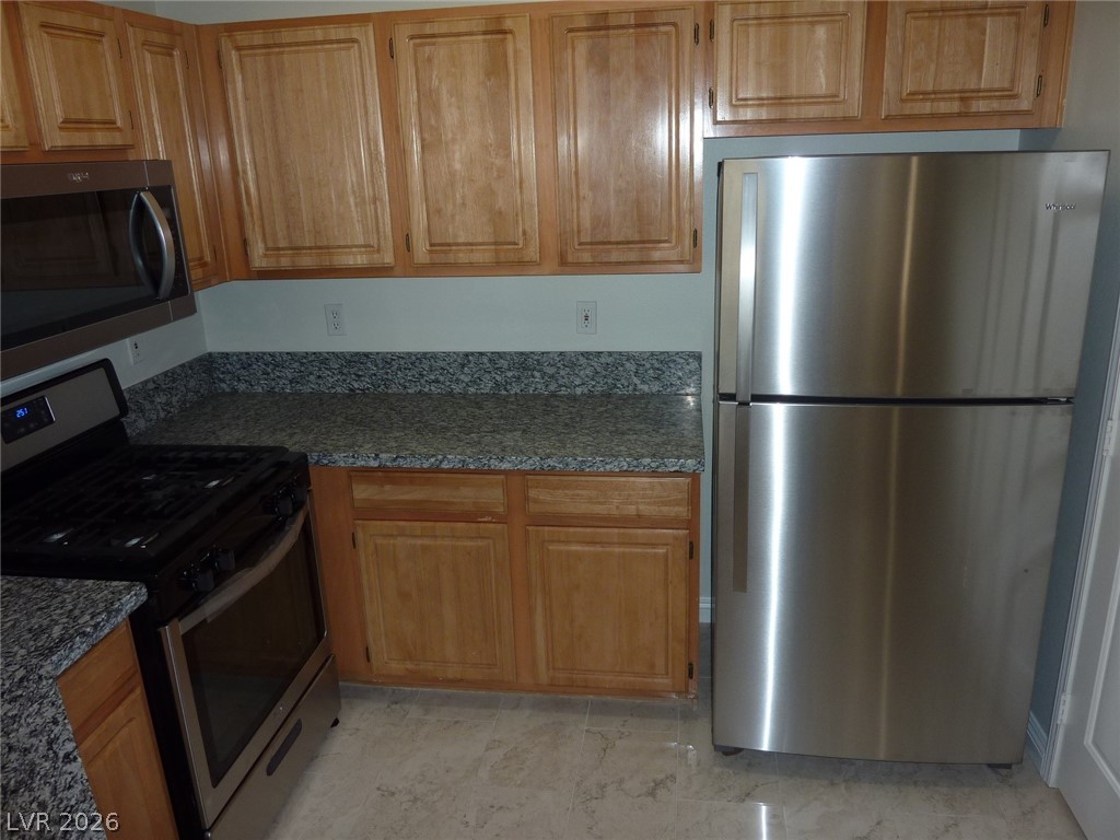 8555 West Russell Road, Unit 2094 Las Vegas, NV 89113 - Photo 12 of 31 Kitchen with stainless steel appliances, dark stone counters, and wood finish cabinetry