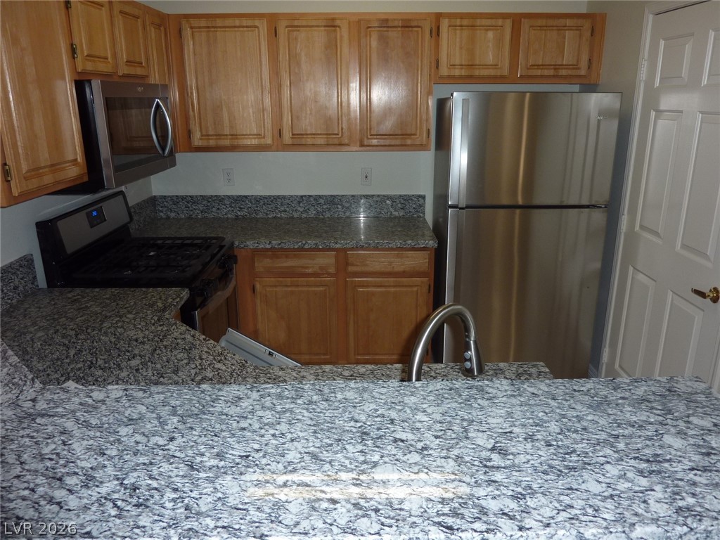 8555 West Russell Road, Unit 2094 Las Vegas, NV 89113 - Photo 9 of 31 Kitchen featuring stainless steel appliances, dark stone countertops, and wood finish cabinetry