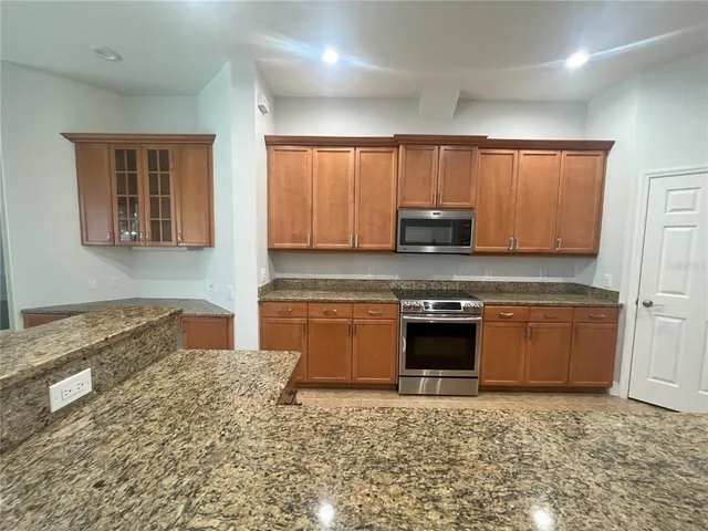 a kitchen with granite countertop a stove top oven sink and cabinets