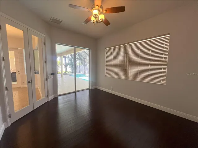 a view of an empty room with wooden floor and a window