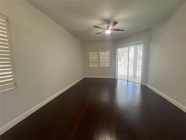 a view of an empty room with a window and wooden floor