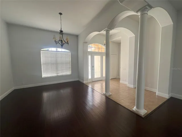 a view of a room with wooden floor chandelier and windows