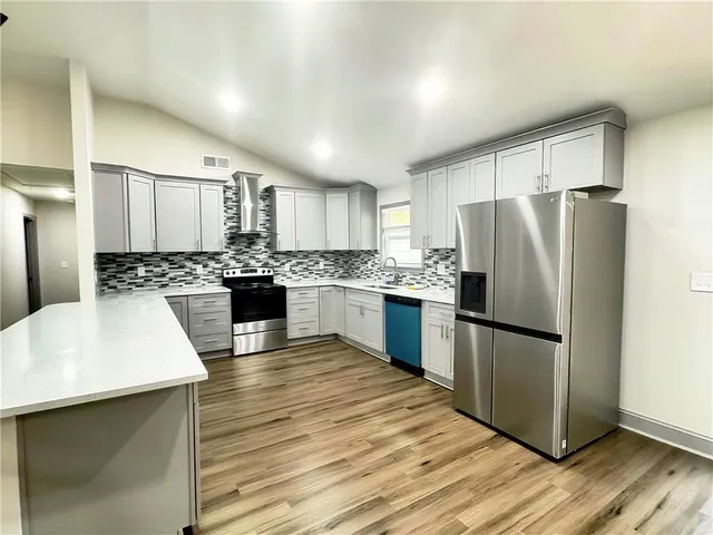 a large kitchen with stainless steel appliances granite countertop a stove and a wooden floors