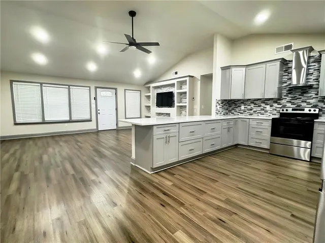 a view of an empty room with wooden floor and a ceiling fan