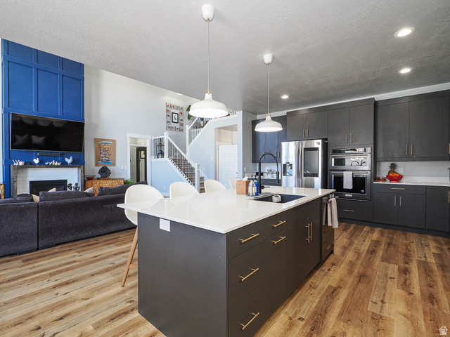 2487 Canyon Wild Road, Unit 413 Draper, UT 84020 - Photo 75 of 75 Kitchen featuring a breakfast bar, open floor plan, decorative light fixtures, a kitchen island with sink, and stainless steel appliances